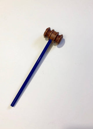 A blue pencil with a wooden gavel head instead of an eraser top, placed on a white surface.