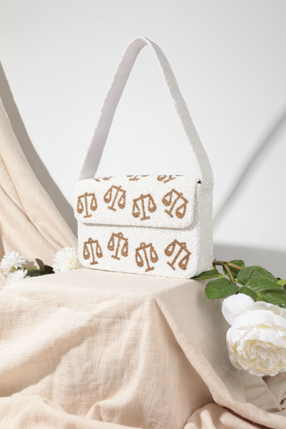 White handbag with gold patterns on a beige fabric background
