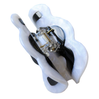 A white and black patterned hair claw clip with a clear plastic spring mechanism, shown on a plain white background.