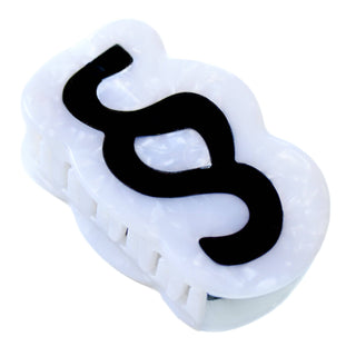 A white marbled claw clip featuring a bold black wavy graphic design on the front, set against a plain white background.