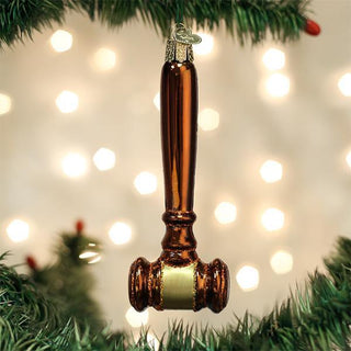 Decorative gavel ornament hanging on a Christmas tree with lights in the background