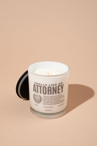 Candle with a label reading 'Smells like an Attorney' on a beige background