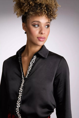 Woman wearing a black blouse with decorative elements on a gray background