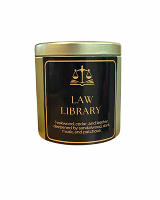 Candle in a tin labeled 'Law Library' with a black and gold design on a white background