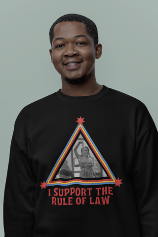 Person wearing a black sweatshirt with a graphic design and text on a plain background